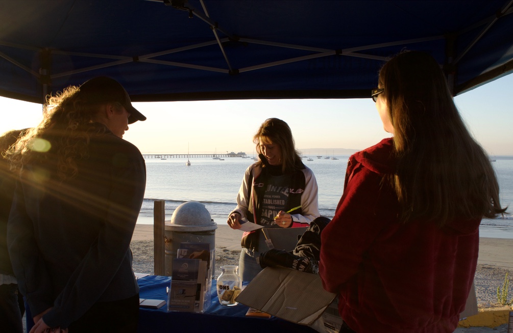 Volunteer Marcia Frank registers the first few participants for that morning's event with a smile despite the early hour. To participate, paddlers paid a price of $40 for non-members and $30 for Surfrider members.